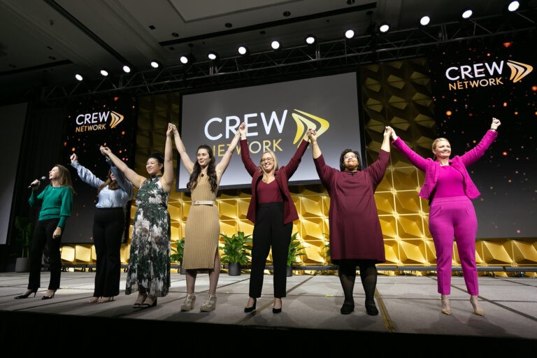 CREW Network small group raising arms on stage